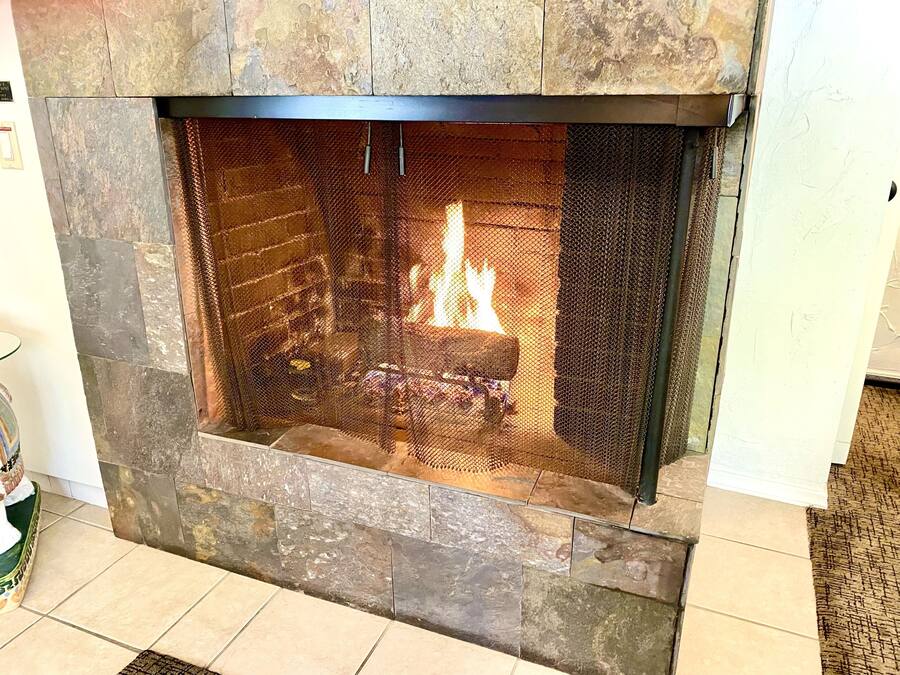 Una chimenea de piedra con fuego encendido, rodeada por un muro de piedra.