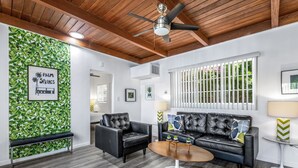 A modern living room with a black leather sofa, a round coffee table, and a ceiling fan. - The Three Fifty Hotel (Palm Springs)