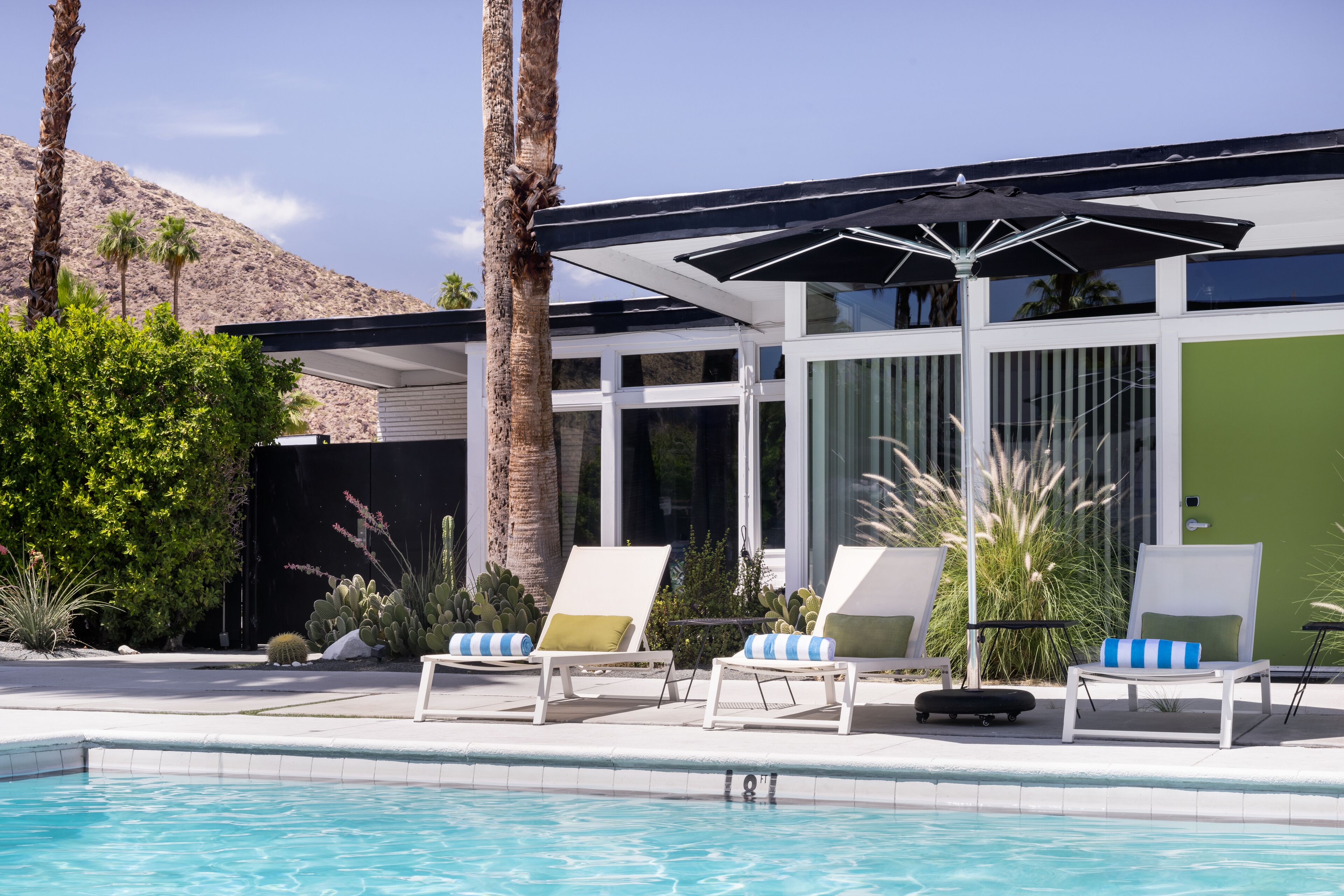 Una piscina al aire libre, sombrillas, sillones reclinables de piscina