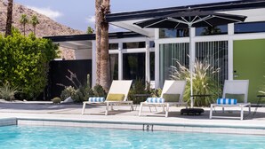 A poolside area with lounge chairs and umbrellas, surrounded by palm trees and cacti. - The Three Fifty Hotel (Palm Springs)