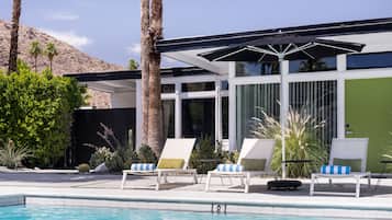 Una piscina al aire libre, sombrillas, sillones reclinables de piscina