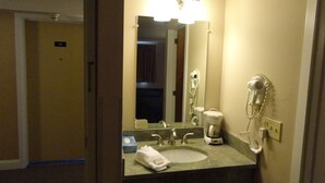 A hotel bathroom with a sink, mirror, hairdryer, and a coffee maker. - Bangor Inn & Suites (Bangor)