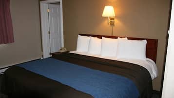 A hotel room with a large bed, a nightstand, a lamp, and a door.