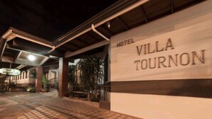 Exterior del Hotel Villa Tournon, con un cartel, un acceso cubierto y un paseo empedrado.
