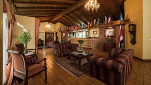 Un vestíbulo espacioso con vigas de madera, un candelabro y una zona de bar con banderas.
