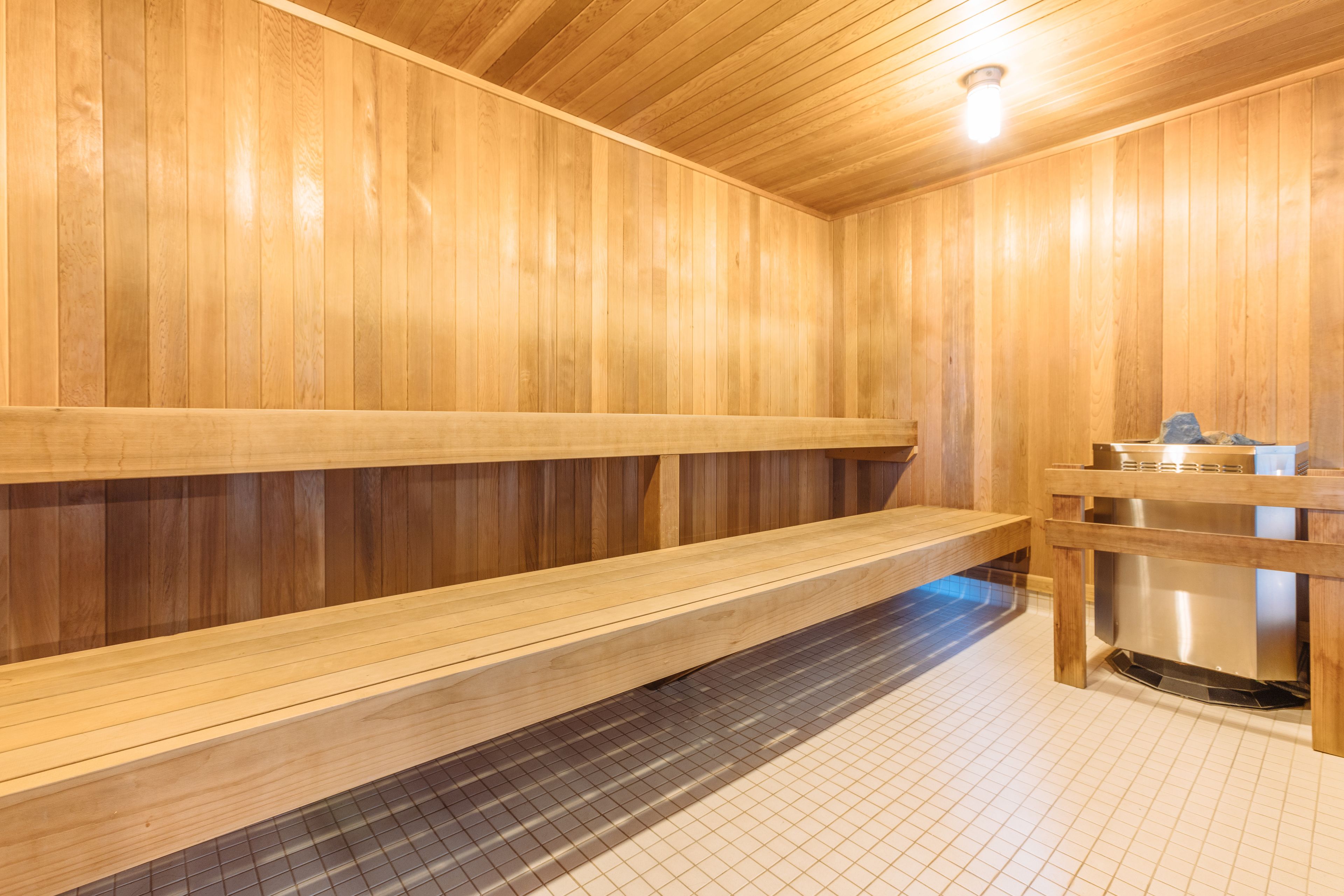 A wooden sauna with benches and a tiled floor.