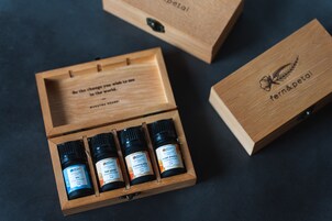 A wooden box with four small bottles of essential oils labeled 'fern&petal'.