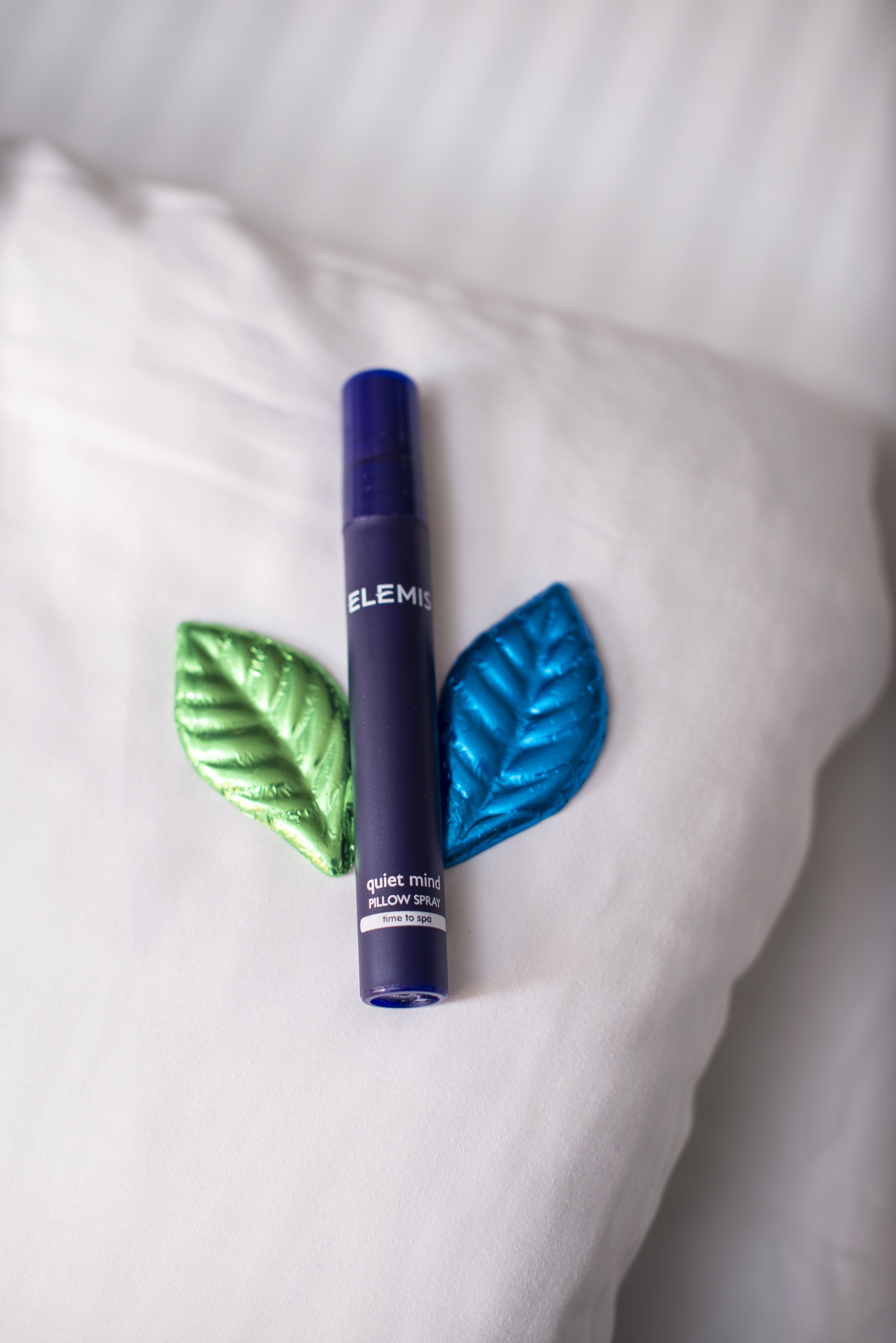 A blue bottle labeled "ELEMIS" with a "quiet mind" spray on a white surface.