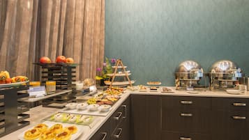 Een buffet met diverse soorten eten, zoals fruit, kazen en gebak.