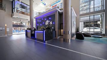Een hotel receptie met een modern ontwerp, met een receptiebalie, zithoek en grote ramen.