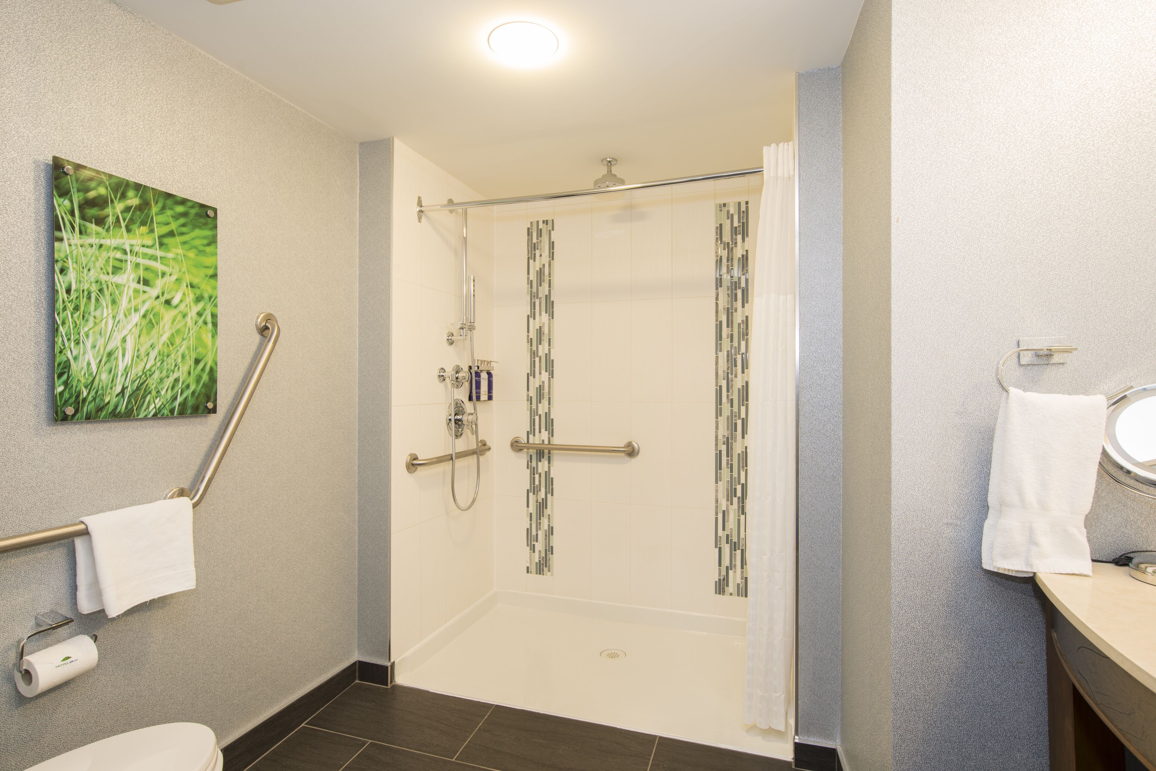 A modern bathroom with a shower, toilet, and sink.