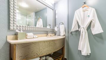 A bathroom with a marble vanity, a large mirror, a robe hanging on a rack, and a towel dispenser.