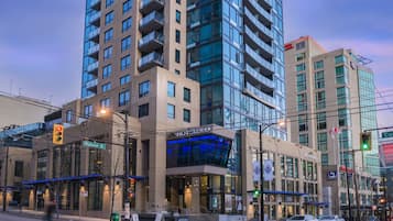 A hotel with a modern glass facade, located at the intersection of Robson St. and another street.