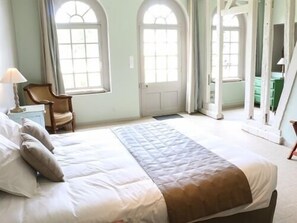 Un dormitorio con cama, una silla y una ventana.