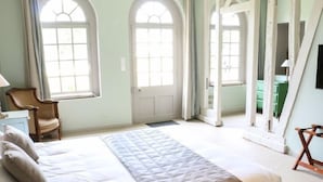 A bedroom with a bed, two windows, a chair, and a mirror. - Le Domaine de Montchevreuil (Montchevreuil)