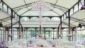A large hall with multiple round tables covered in white tablecloths, clear chairs, and floral centerpieces. - Le Domaine de Montchevreuil (Montchevreuil)