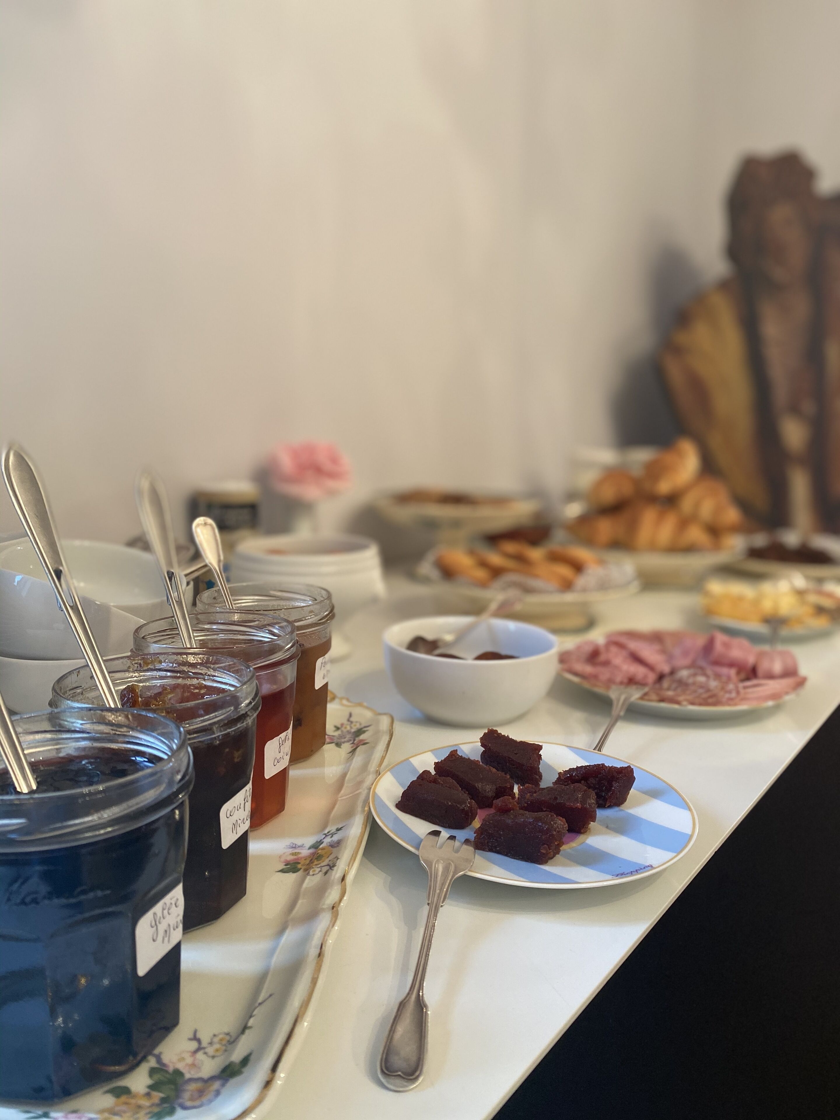 A buffet table with various food items including jars of jam, a plate of brownies, and a bowl of soup.