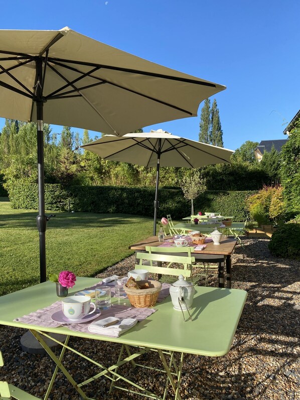 An outdoor dining area with tables and chairs, surrounded by greenery and a clear sky. - La Maison D'aline (Pennedepie)