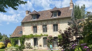 A stone house with a tiled roof, a garden with peonies, and a clear sky. - La Maison D'aline (Pennedepie)