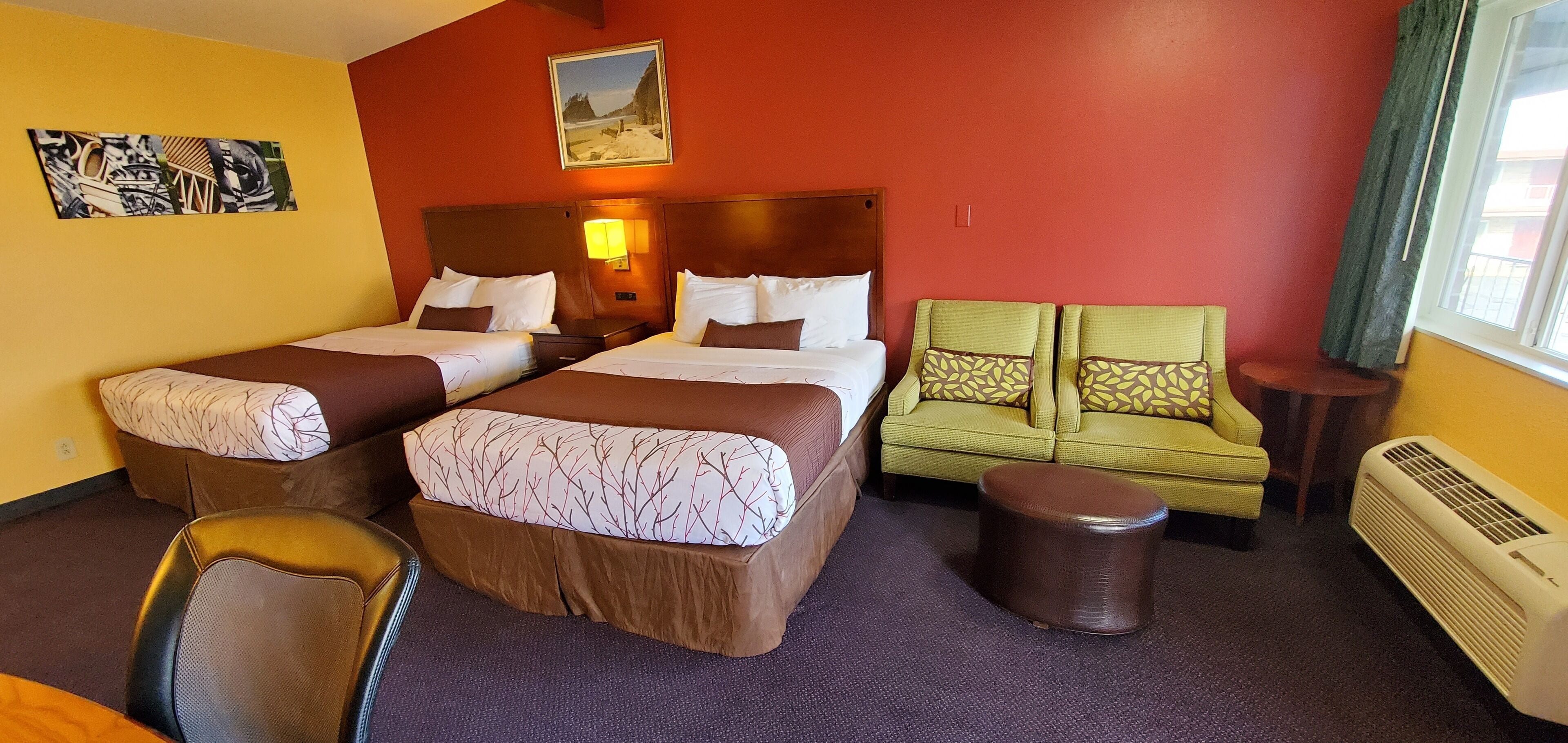 Una habitación de hotel con dos camas, un sofá verde, una silla y una mesita.