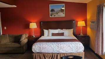 Una habitación de hotel con una cama grande, dos lámparas de noche, una silla, un cuadro en la pared y una ventana con cortinas.