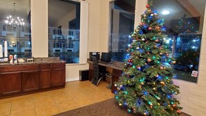 Una cocina moderna con una isla grande, un árbol de Navidad y ventanas amplias que ofrecen vistas al exterior.