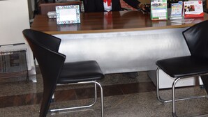 Un comptoir d’accueil équipé d’un écran d’ordinateur, d’un téléphone et d’un présentoir à brochures.