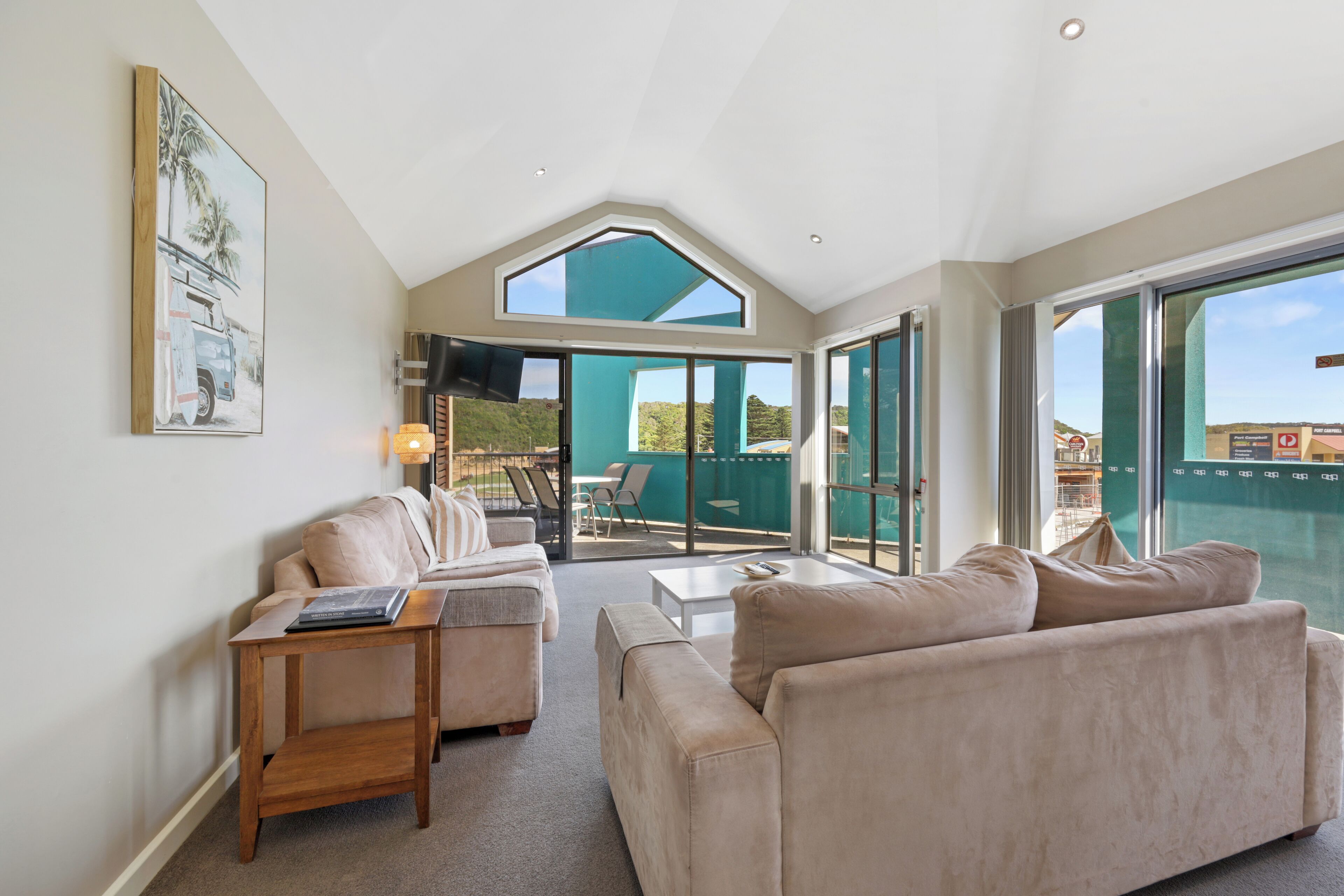A spacious living room with a high ceiling, a large window, and a view of the outdoors.