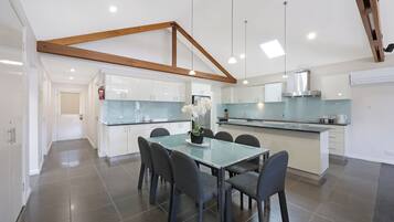 A modern kitchen with white cabinets, a central island, and a dining area with a glass table and chairs.