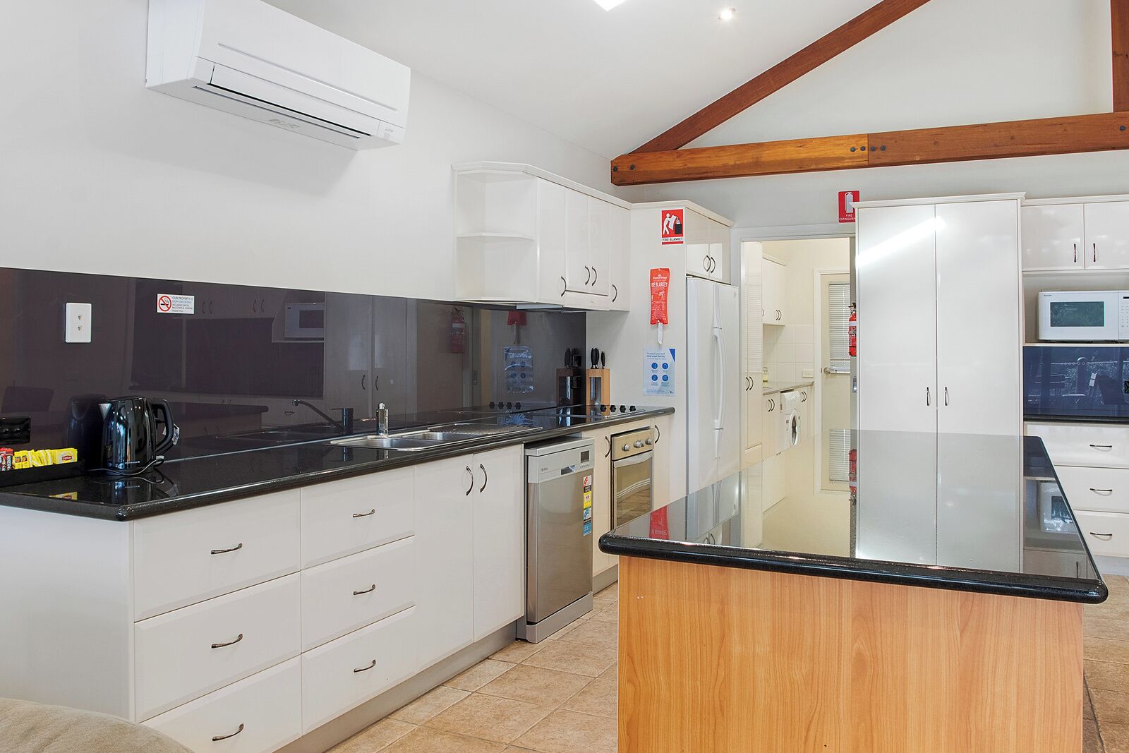 A modern kitchen with white cabinets, a black countertop, and stainless steel appliances.