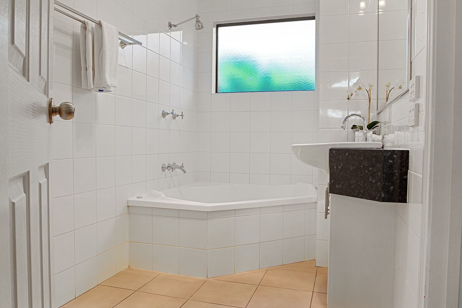 Un baño con bañera, ventana con vistas y lavabo con encimera de mármol.
