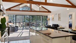 Una cocina moderna con una isla grande, vigas de madera y ventanas amplias con vistas al exterior.