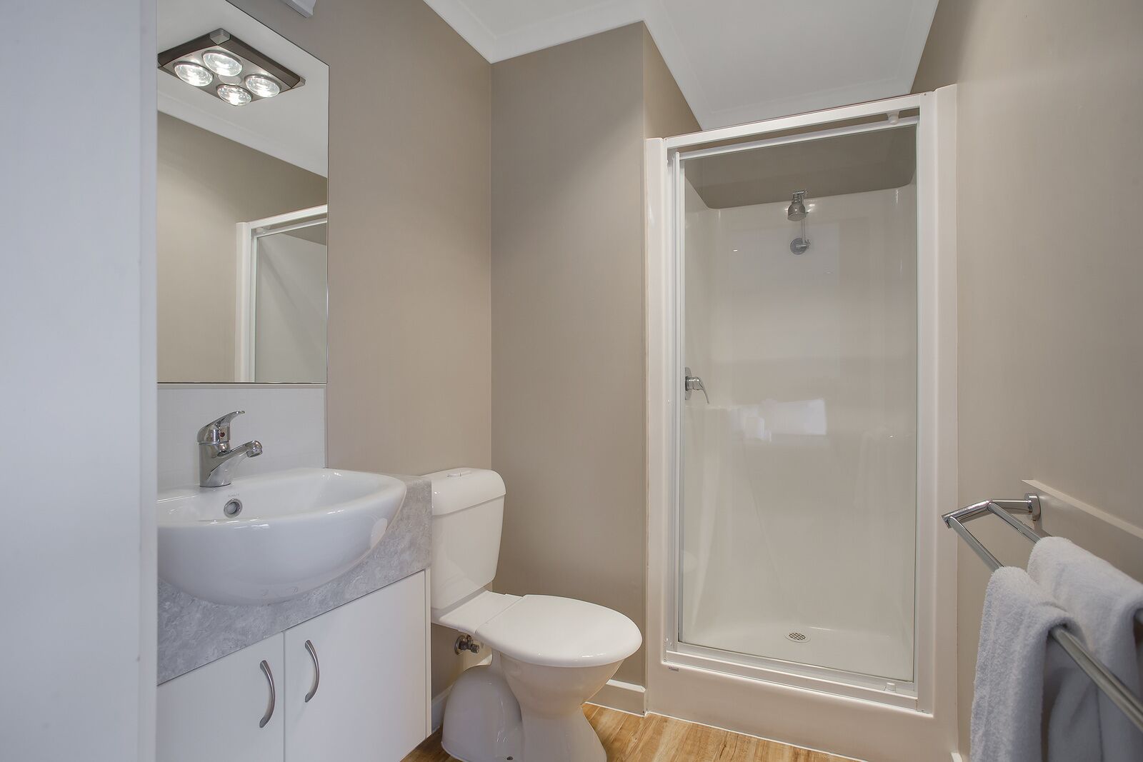 Une salle de bain moderne avec un lavabo blanc, des toilettes et une douche à parois de verre.