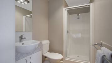 Une salle de bain moderne avec un lavabo blanc, des toilettes et une douche à parois de verre.