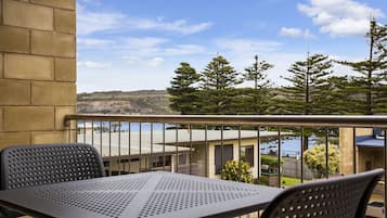 Enjoy a serene coastal view from this balcony with a table and two chairs.
