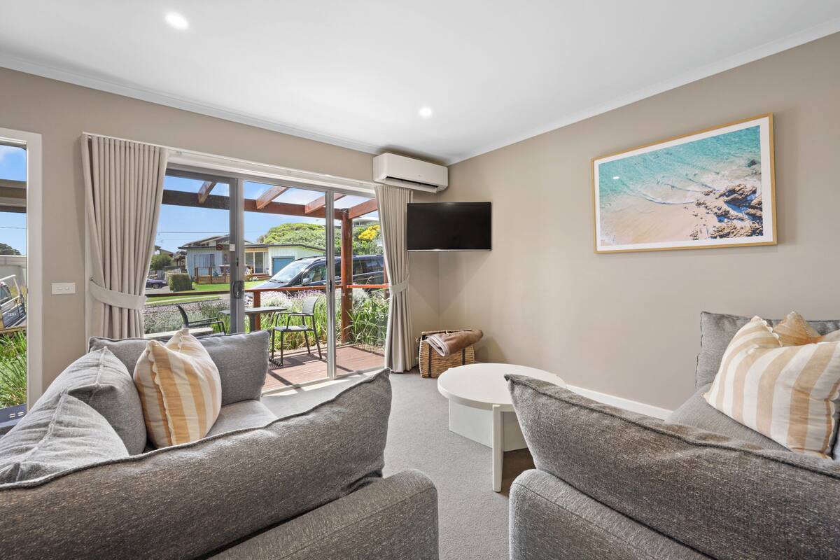 A modern living room with a sofa set, a small round table, and a large window with curtains.