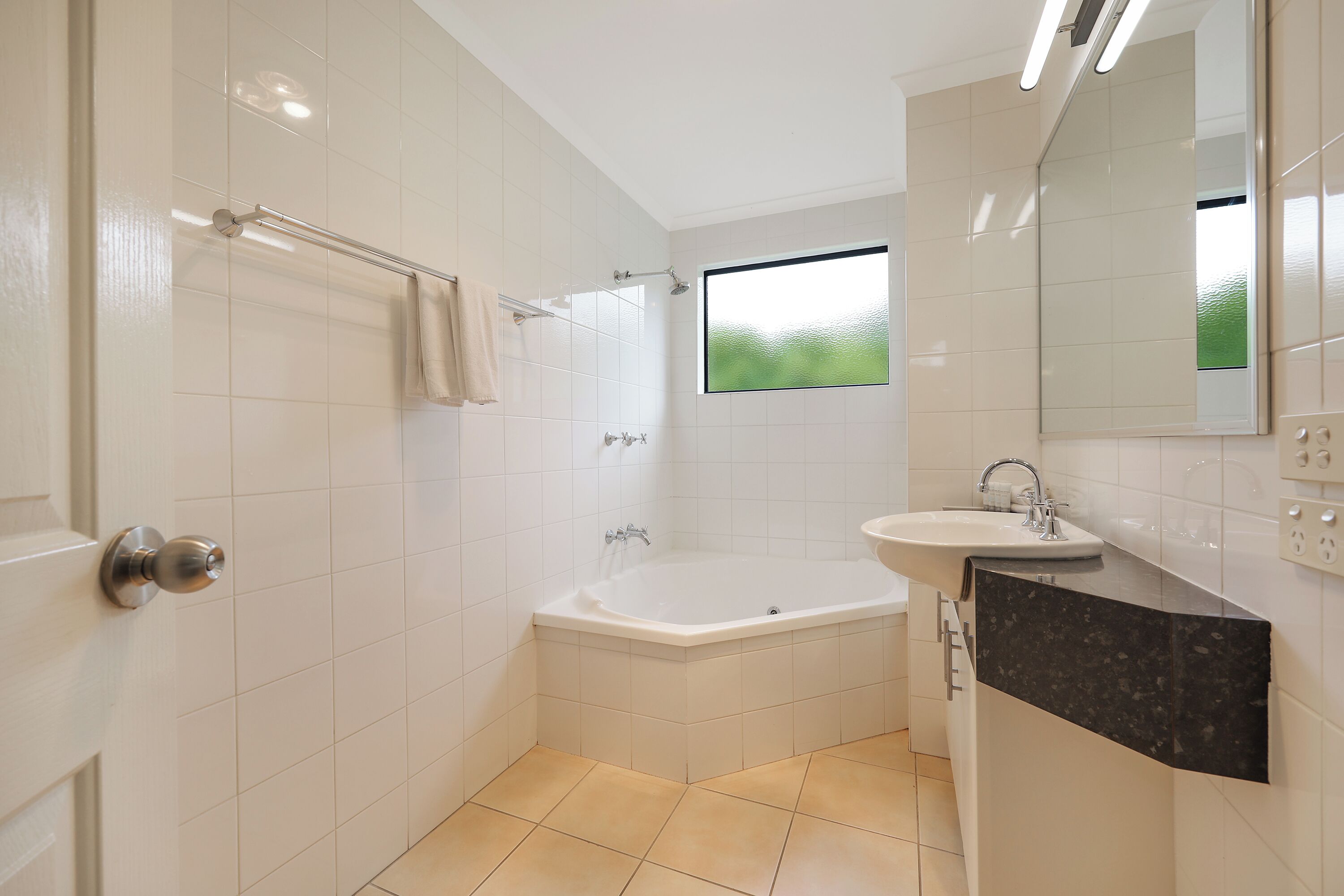 A modern bathroom with a bathtub, a sink, and a window.