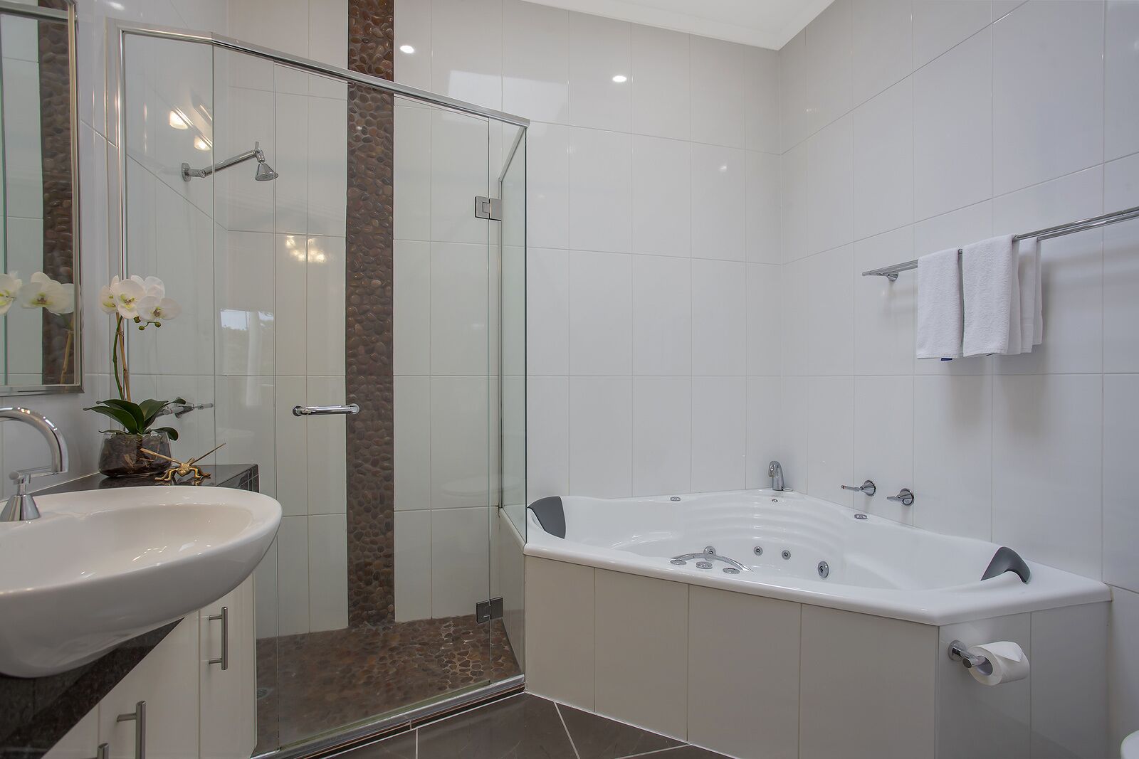 Un baño moderno con ducha de vidrio, una bañera independiente y un lavabo blanco.