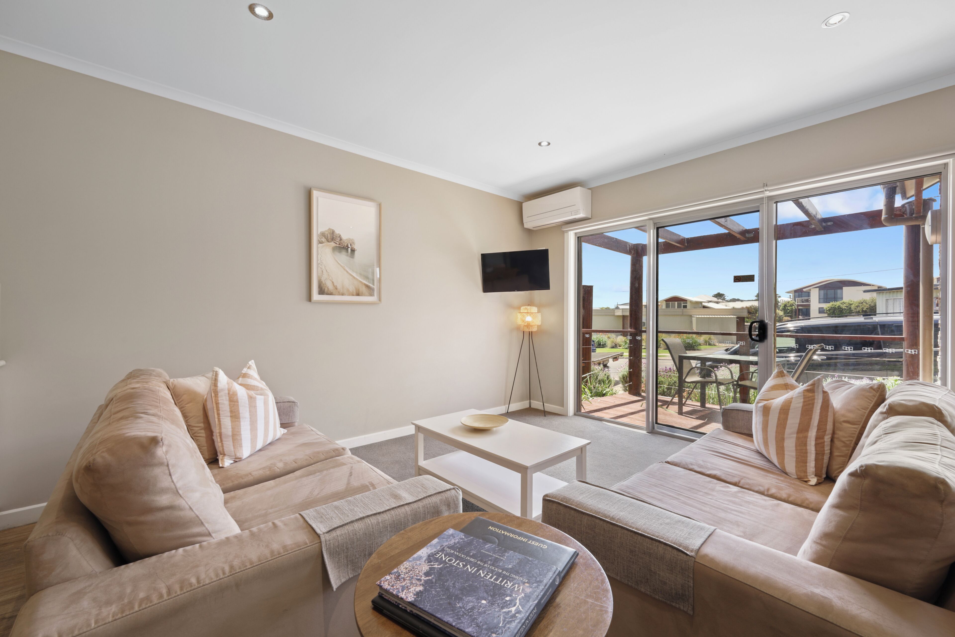 A modern living room with beige sofas, a coffee table, and a flat-screen TV.