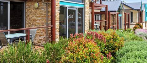A modern building with stone and glass facade, outdoor seating, and well-maintained landscaping.