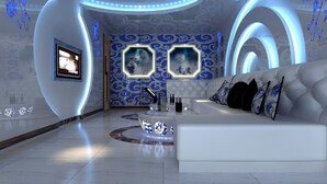 A modern living room with a white sofa, a TV mounted on the wall, and decorative wall art. - BORRMAN Hotel (Guangzhou)