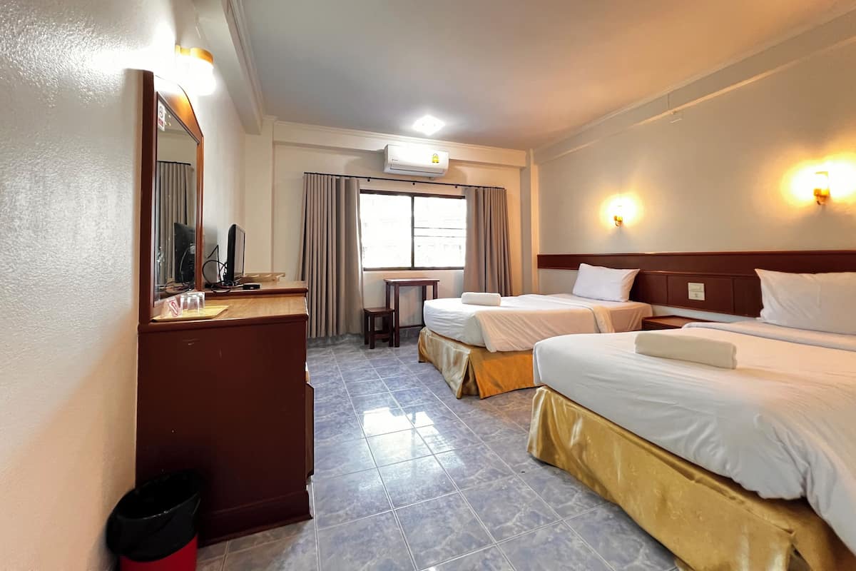 Habitación de hotel con dos camas, un escritorio, una silla, un cesto de basura y un equipo de aire acondicionado.