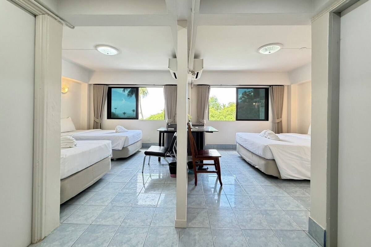 Habitación de hotel con dos camas, un escritorio y vistas a zonas verdes.