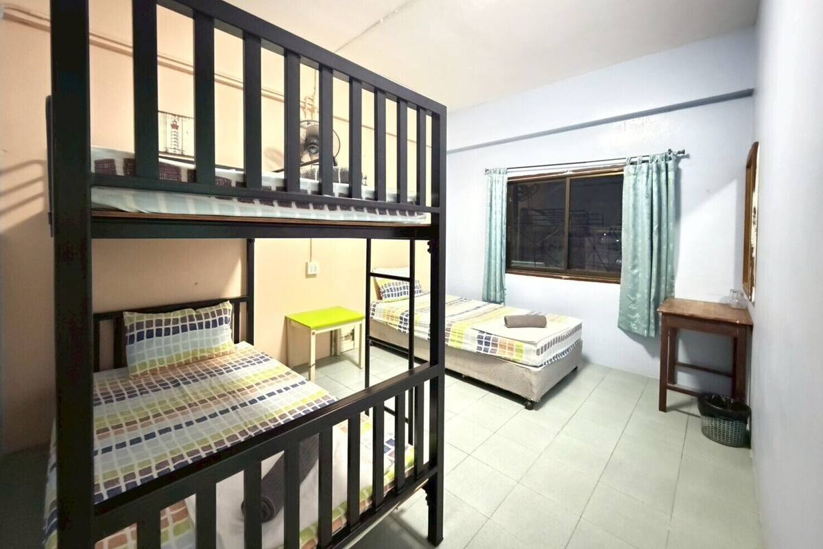 Un dormitorio con literas, un escritorio pequeño, una ventana con cortinas y un espejo en la pared.