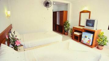 Una habitación de hotel con dos camas, un escritorio con computadora, un espejo y un ventilador.