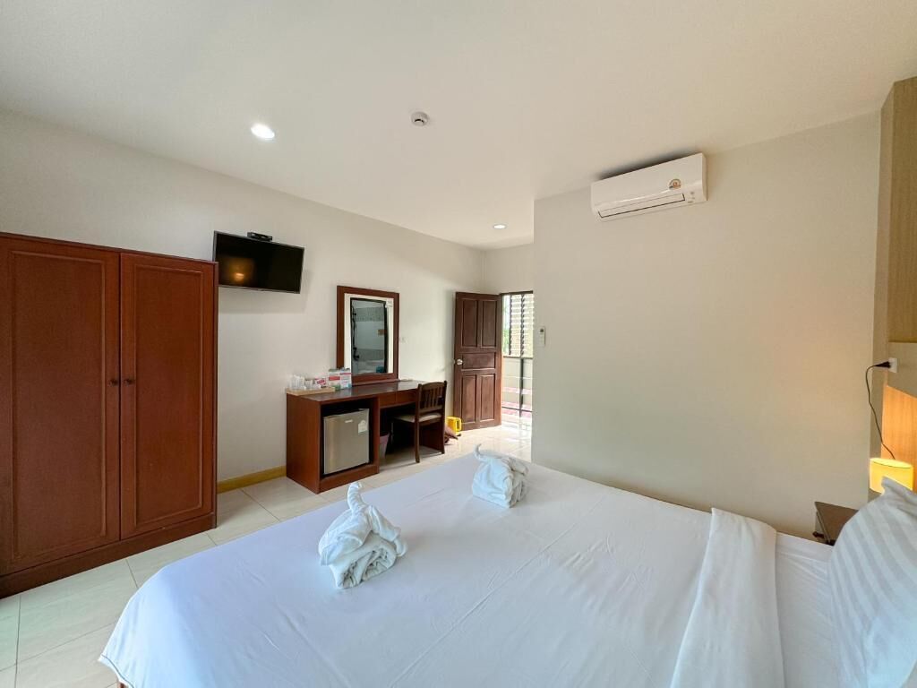 A hotel room with a bed, a desk, a TV, and a wardrobe.