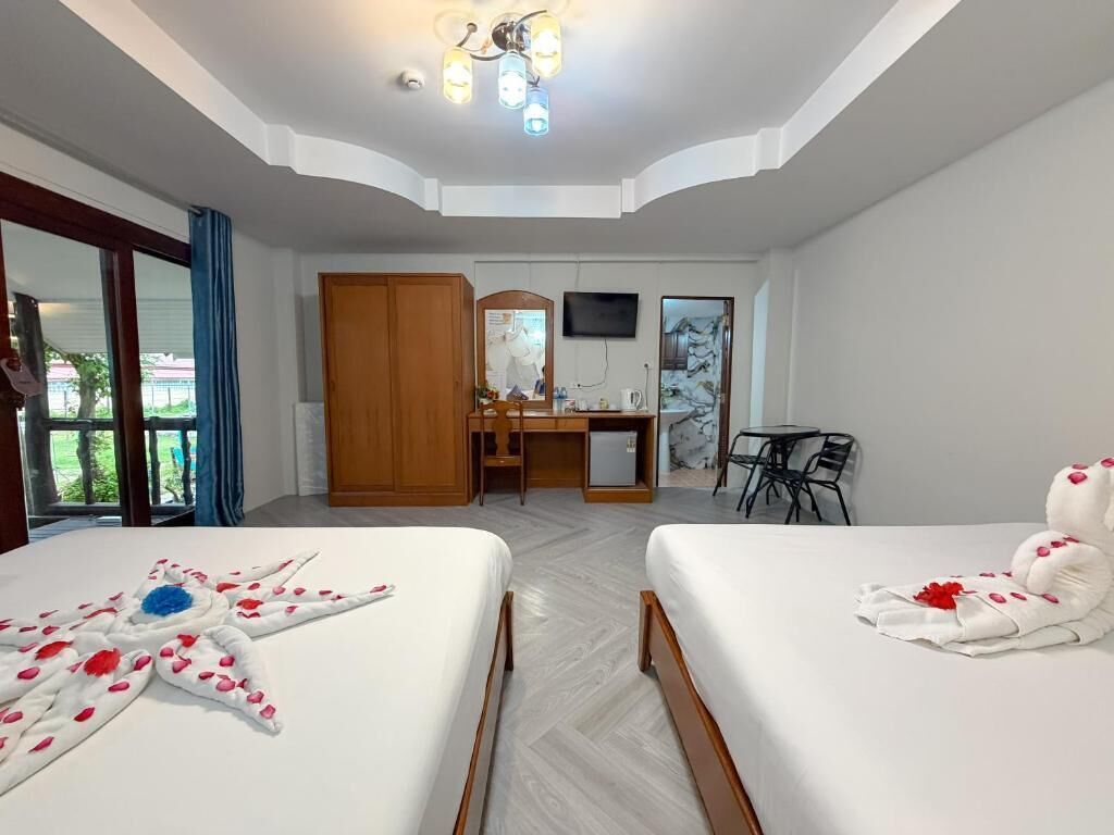 A hotel room with two beds, a desk, a chair, a TV, and a balcony.