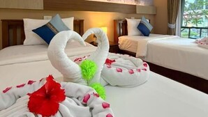 A hotel room with two beds, floral wall art, and a view of greenery outside. - Chongkhao Resort (Ko Phi Phi)