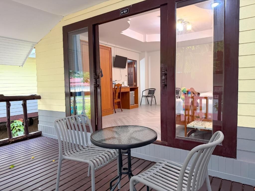 Un patio techado con una mesa y sillas, una terraza de madera y vistas hacia una habitación con comedor.