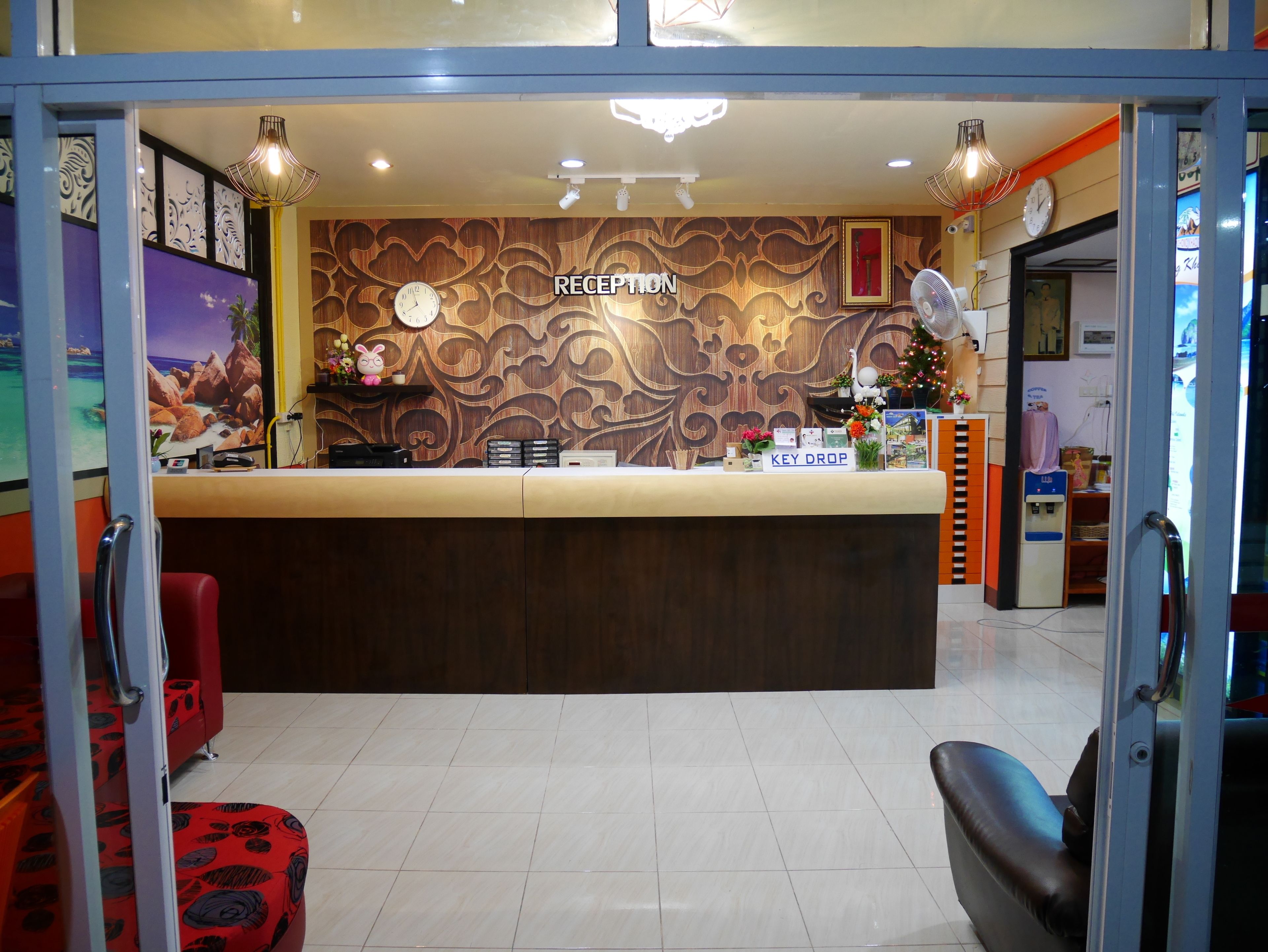 Un espace d’accueil avec un mur décoré de motifs en bois, une horloge et un panneau indiquant « DÉPOSEZ VOS CLÉS ».